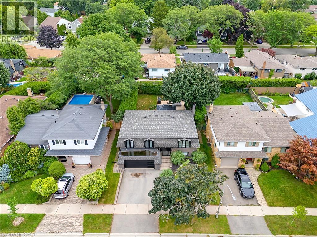Contemporary residence featuring a paved driveway, attached garage, and mature landscaping - 4236 Longmoor Drive, Burlington, ON