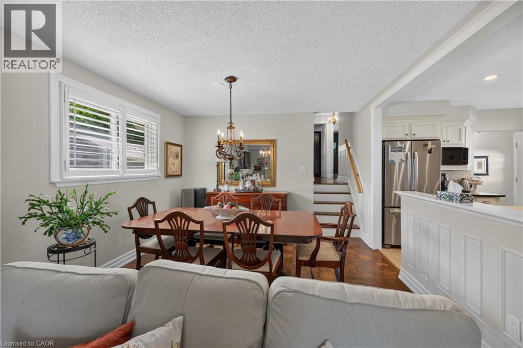Dining area with wood-finish flooring, white window shutters, and a chandelier - 1434 Dewbourne Crescent, Burlington, ON