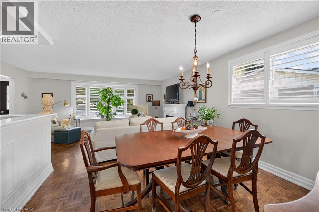 Wood-finish parquet flooring, white wall paneling, white window shutters, and a decorative chandelier - 1434 Dewbourne Crescent, Burlington, ON