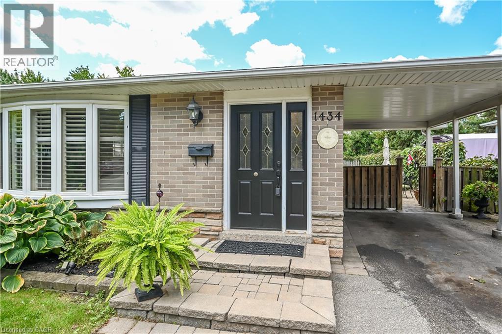Brick and stone facade featuring a bay window with plantation shutters, a dark entry door with decorative glass, and a covered carport - 1434 Dewbourne Crescent, Burlington, ON