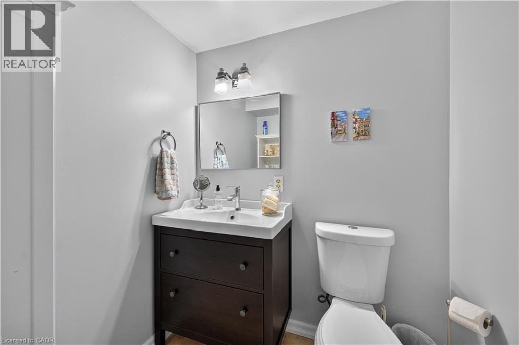 Vanity with integrated sink, dark wood-finish cabinetry, chrome faucet, and rectangular mirror - 1434 Dewbourne Crescent, Burlington, ON