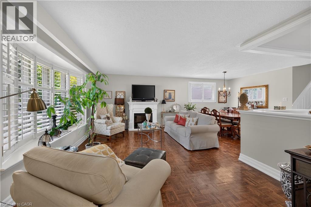 Bay window with interior shutters, wood-finish flooring, white mantel fireplace, ceiling-mounted light fixture, and crown molding - 1434 Dewbourne Crescent, Burlington, ON