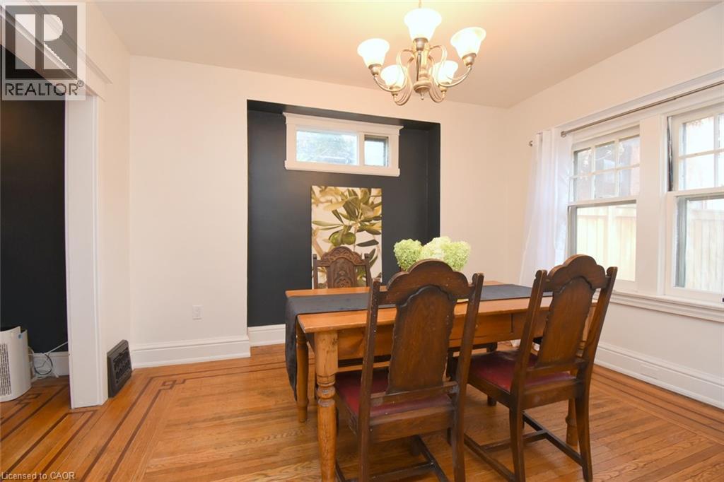 Hardwood flooring with border inlay, white trim, recessed wall feature with window, and a chandelier - 35 Tisdale Street S, Hamilton, ON