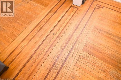 Hardwood flooring throughout featuring warm wood-finish planks laid in a diagonal herringbone pattern, showcasing rich amber and honey tones with natural grain variation and a polished finish - 35 Tisdale Street S, Hamilton, ON 