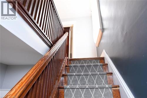 Staircase featuring wood-finish banisters and a patterned stair runner - 35 Tisdale Street S, Hamilton, ON 