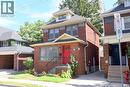 Brick exterior with a prominent red door, front porch with black railings, and a dormer window - 35 Tisdale Street S, Hamilton, ON 