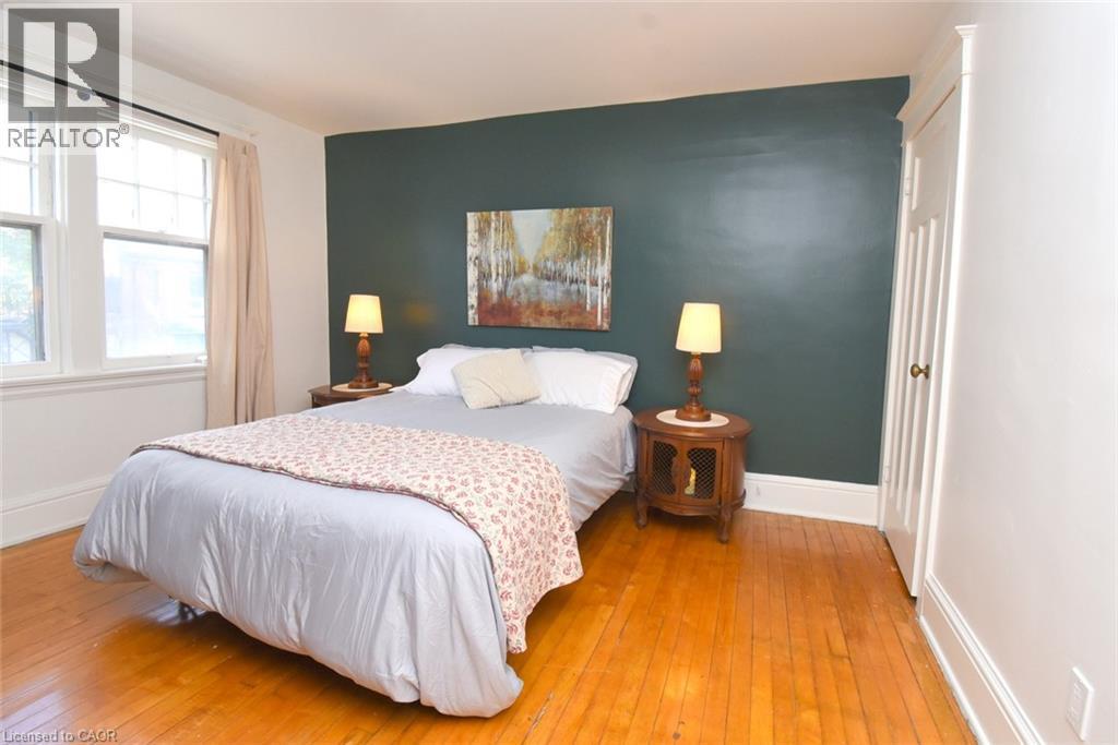 Hardwood flooring, painted accent wall, windows with trim, and a built-in closet with panel detailing - 35 Tisdale Street S, Hamilton, ON