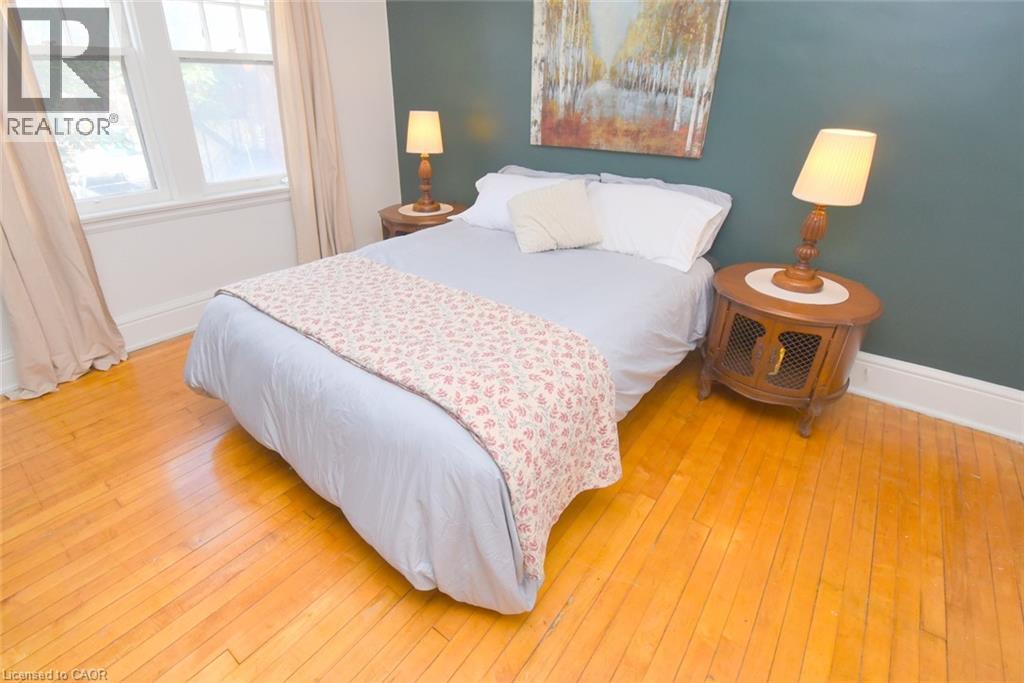 Hardwood flooring, painted accent wall, white trim, and a double window - 35 Tisdale Street S, Hamilton, ON