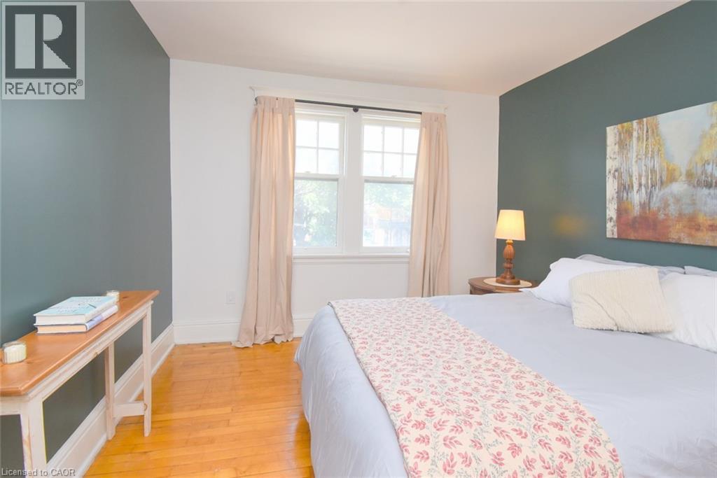 Hardwood flooring throughout, featuring a double-hung window with natural light, and a painted accent wall - 35 Tisdale Street S, Hamilton, ON