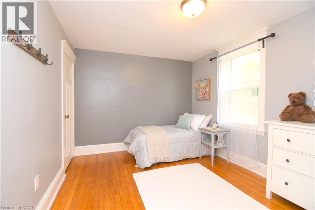 Hardwood flooring, painted walls, white trim, single window with opaque curtain, and a ceiling-mounted light fixture - 35 Tisdale Street S, Hamilton, ON