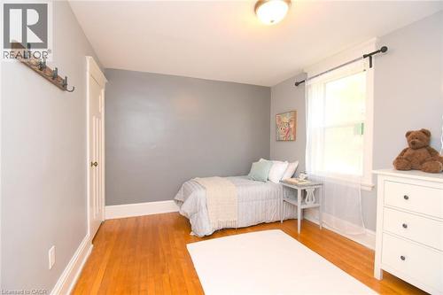 Hardwood flooring, painted walls, white trim, single window with opaque curtain, and a ceiling-mounted light fixture - 35 Tisdale Street S, Hamilton, ON 