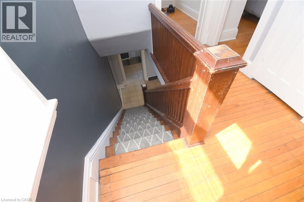 Wood-finish flooring with a patterned stair runner and a wood newel post and balusters - 35 Tisdale Street S, Hamilton, ON
