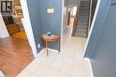 Tiled flooring entry with a wood-finish staircase featuring a patterned runner and dark wood newel post - 35 Tisdale Street S, Hamilton, ON 