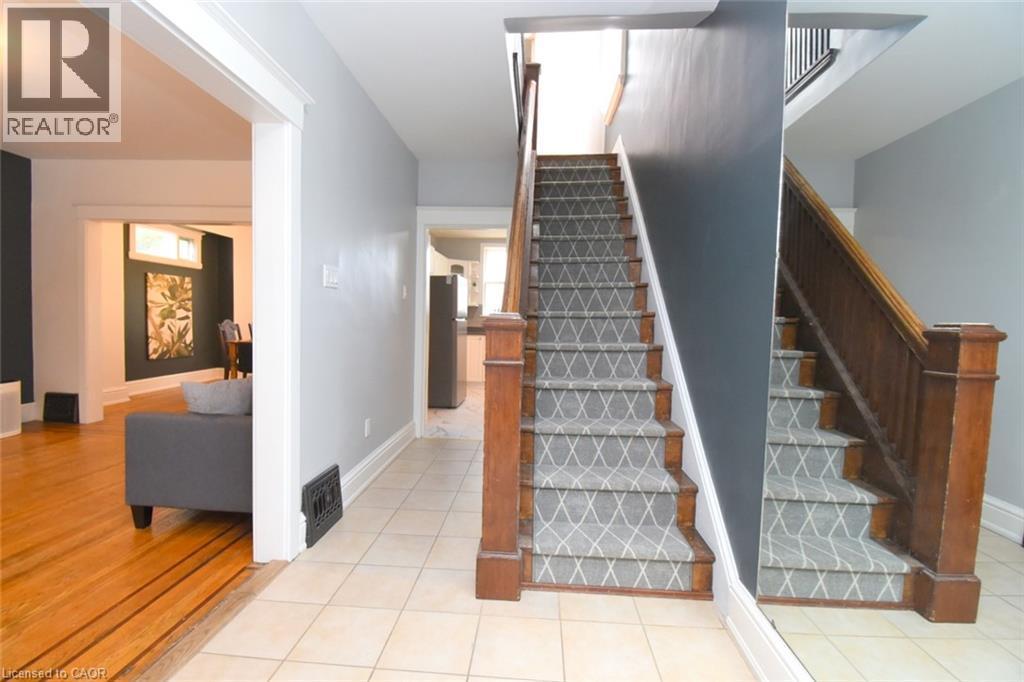 Tiled flooring entryway with a staircase featuring a wood railing and patterned runner - 35 Tisdale Street S, Hamilton, ON