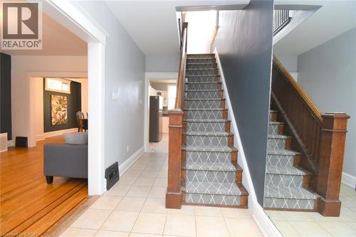 Tiled flooring entryway with a staircase featuring a wood railing and patterned runner - 35 Tisdale Street S, Hamilton, ON 