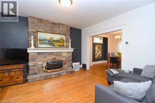 Stone-clad fireplace with mantel, hardwood flooring, and cased opening to a separate room - 35 Tisdale Street S, Hamilton, ON 