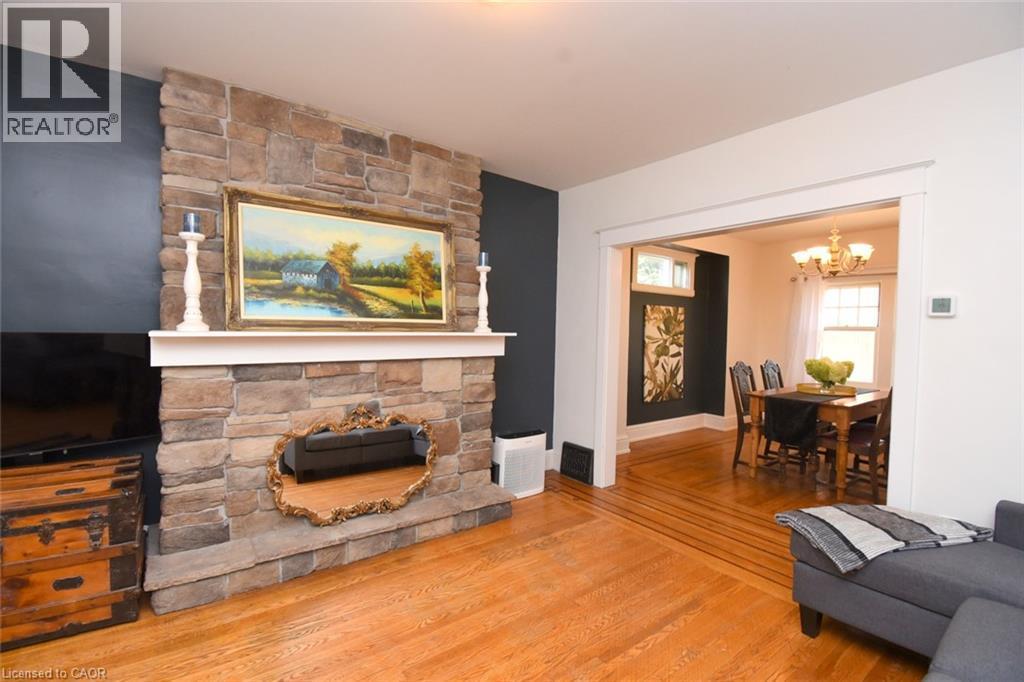 Stone fireplace with a white mantel, wood-finish flooring, and a cased opening to an additional room - 35 Tisdale Street S, Hamilton, ON