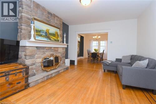 Stone-clad fireplace with mantel, hardwood flooring, recessed ceiling lighting, and a broad cased opening to the dining area - 35 Tisdale Street S, Hamilton, ON 