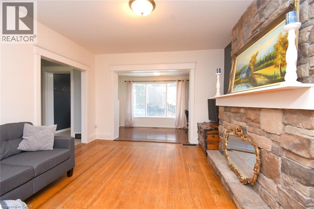 Hardwood flooring throughout, stone-clad fireplace with a substantial hearth and mantel, neutral wall tones, and recessed doorways - 35 Tisdale Street S, Hamilton, ON