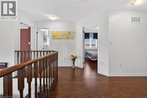 Hall with a textured ceiling, dark wood finished floors, and an upstairs landing - 97 Sirente Drive, Hamilton, ON 