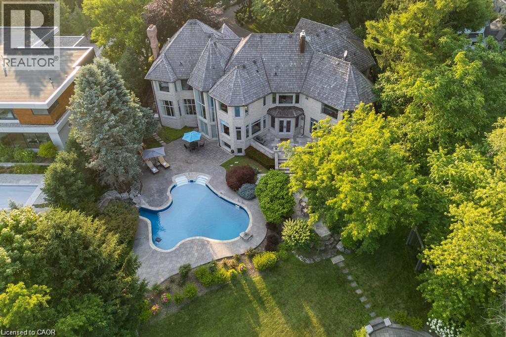 Expansive property featuring a multi-level structure with multiple gables, a large free-form swimming pool, and a paver patio surround - 4038 Lakeshore Road, Burlington, ON