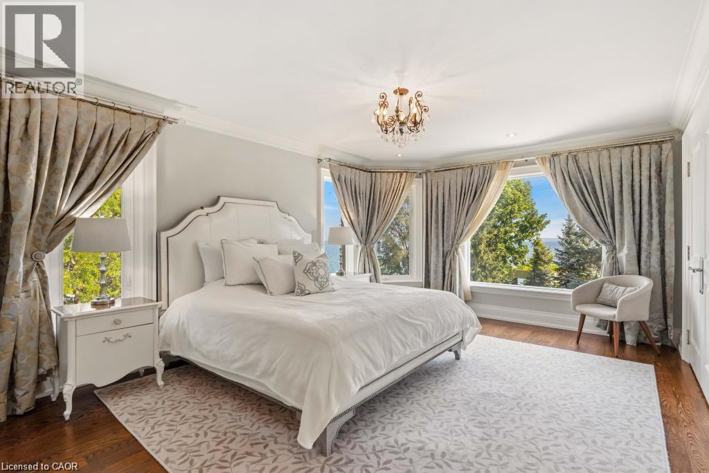 Bay window offering expansive scenery, dark wood-finish flooring, ornate chandelier, and white paneled door - 4038 Lakeshore Road, Burlington, ON