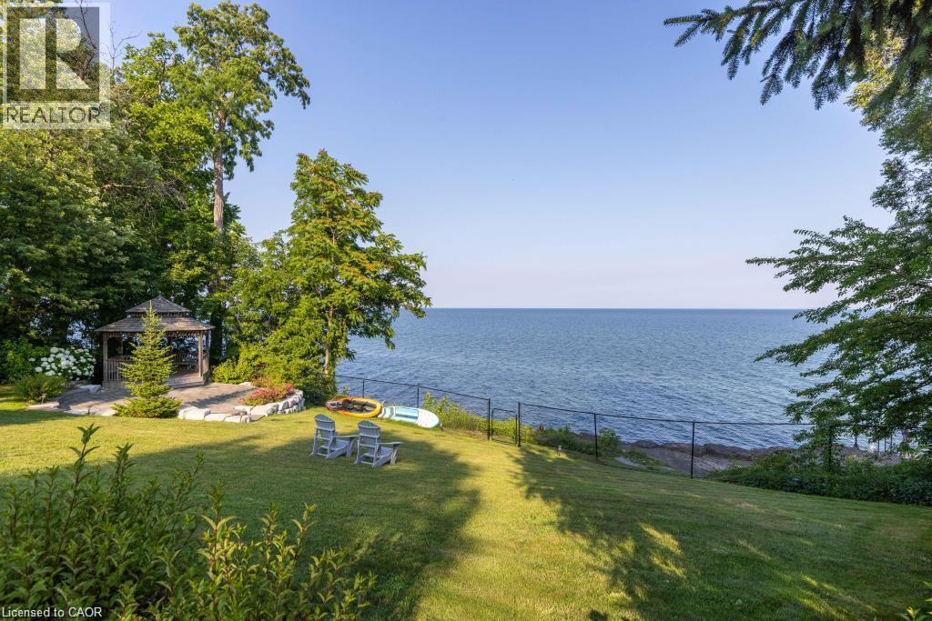 Expansive green lawn with mature trees and a charming gazebo, overlooking a vast body of water - 4038 Lakeshore Road, Burlington, ON
