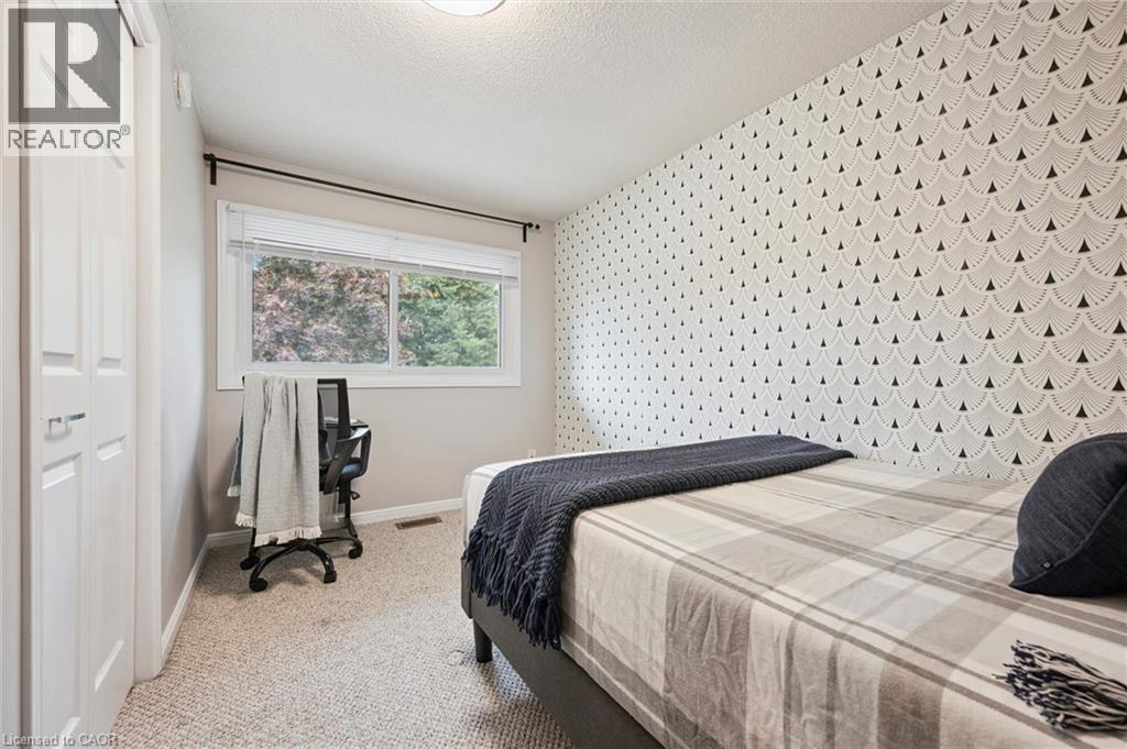 Textured accent wall, neutral carpeting, white trim, and a window with natural light - 21 Colebrook Court, Kitchener, ON