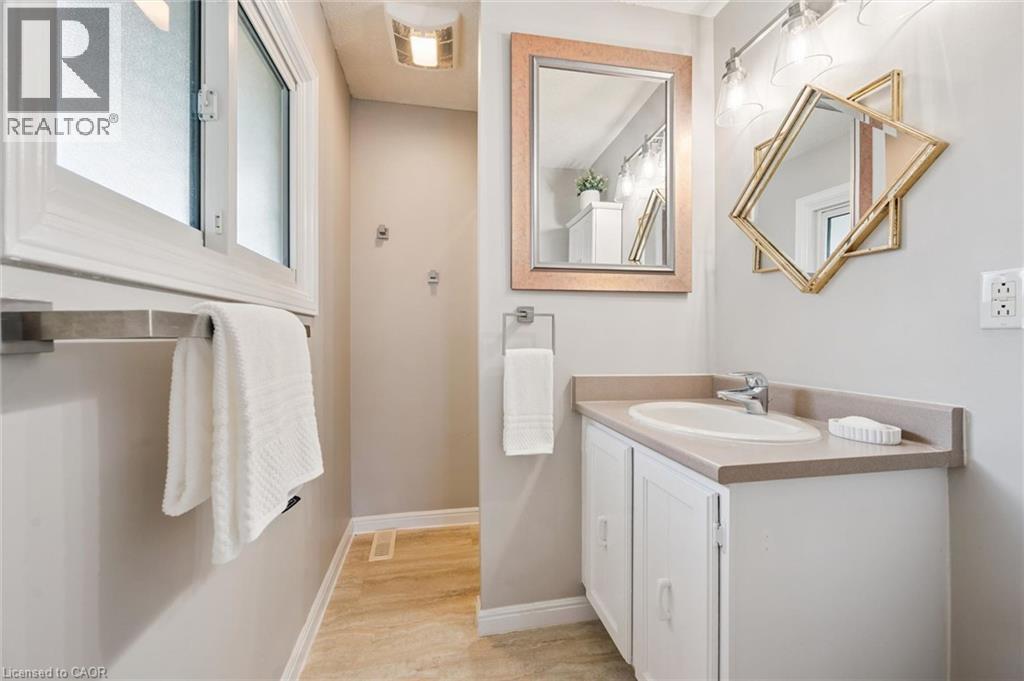 White vanity with an integrated sink and countertop, track lighting fixture, and frosted window - 21 Colebrook Court, Kitchener, ON