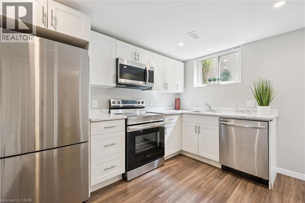 White shaker cabinetry, stainless steel appliances, light-toned countertops, wood-finish flooring, and recessed lighting - 21 Colebrook Court, Kitchener, ON