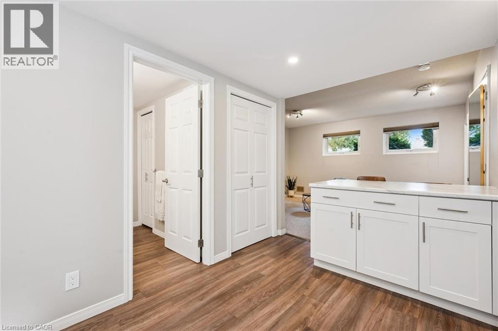 Wood-finish flooring, white cabinetry with a light-toned countertop, recessed lighting, and track lighting fixtures - 21 Colebrook Court, Kitchener, ON