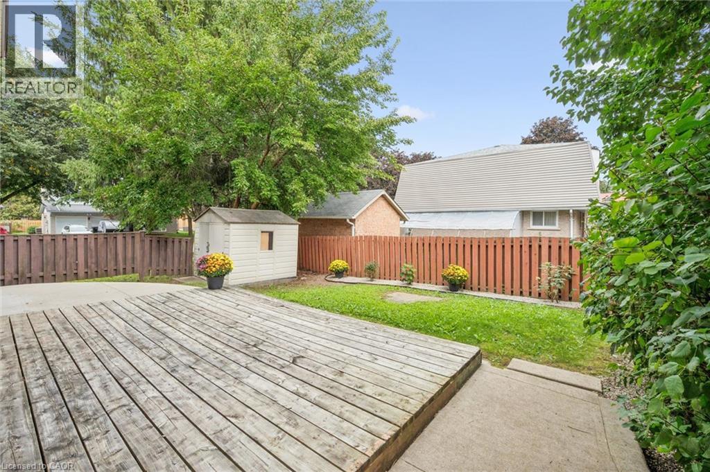 Expansive wood deck with a privacy fence, concrete patio, and a storage shed - 21 Colebrook Court, Kitchener, ON