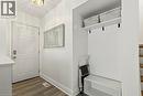 Entryway featuring a decorative ceiling light fixture, wood-finish flooring, and a built-in storage bench with an upper shelf - 27 Gretna Court, Hamilton, ON 