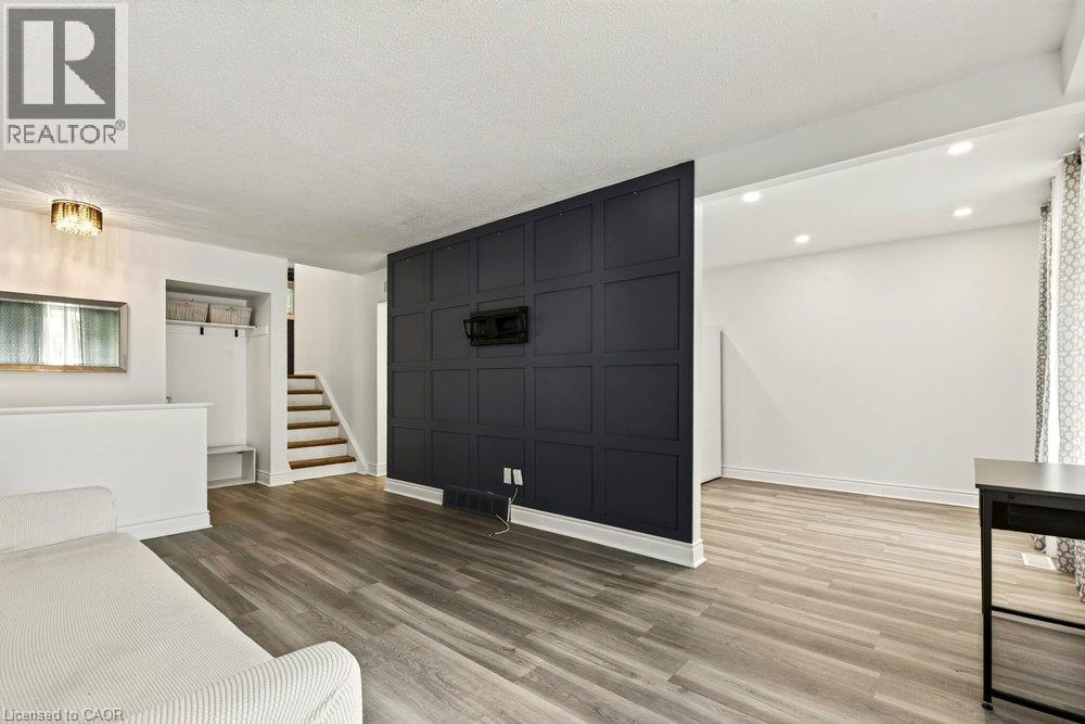 Wood-finish flooring throughout, featuring a dark accent wall with paneling - 27 Gretna Court, Hamilton, ON