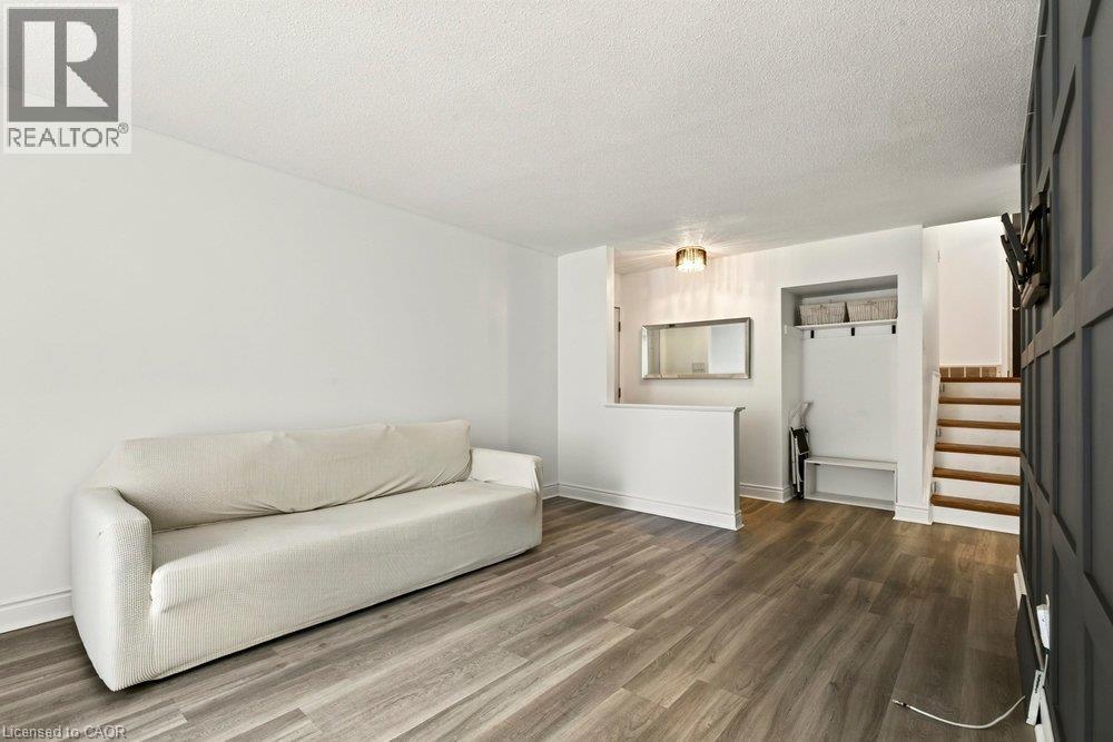 Wood-finish flooring throughout, white walls, built-in entryway storage with shelving and hooks, and a paneled wall feature - 27 Gretna Court, Hamilton, ON