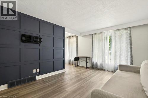 Accent wall with paneling, wood-finish flooring, and multiple windows - 27 Gretna Court, Hamilton, ON 