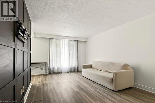 Wood-finish flooring throughout, complemented by a decorative paneled accent wall and white painted walls - 27 Gretna Court, Hamilton, ON 