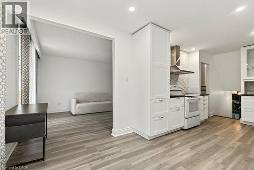 Recessed lighting, wood-finish flooring, white cabinetry, dark countertops, and a tile backsplash - 27 Gretna Court, Hamilton, ON 