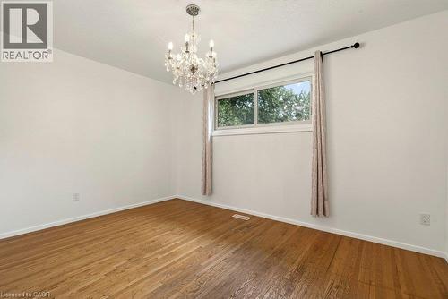 Hardwood flooring, crystal chandelier, white walls, and a window with a black curtain rod - 27 Gretna Court, Hamilton, ON 