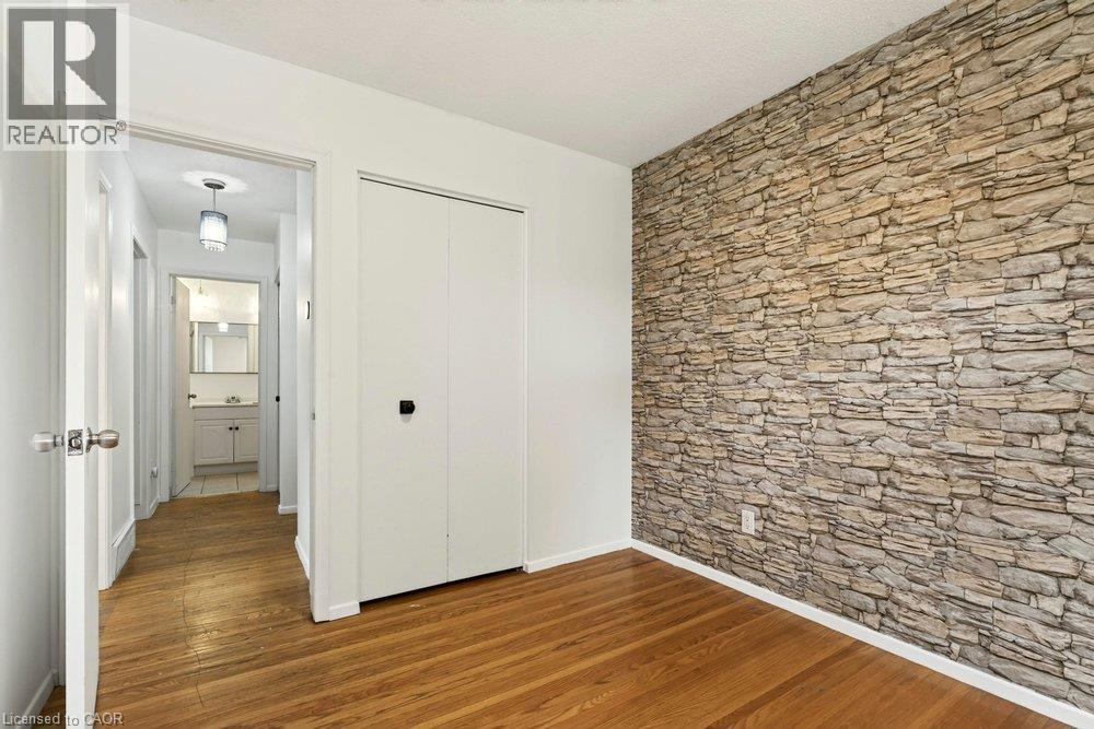 Wood-finish flooring with a stone-finish accent wall - 27 Gretna Court, Hamilton, ON