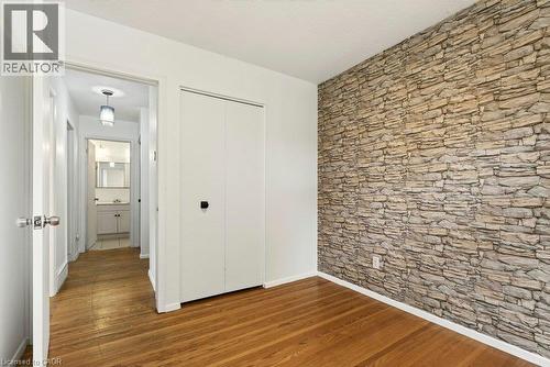Wood-finish flooring with a stone-finish accent wall - 27 Gretna Court, Hamilton, ON 