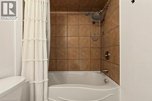 Built-in bathtub with shower head and handheld shower, bronze-finish fixtures, and tiled surround - 27 Gretna Court, Hamilton, ON 