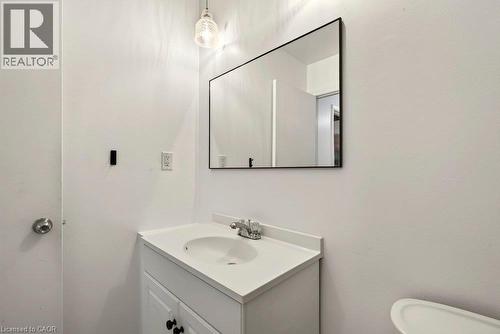 White vanity with an integrated sink, polished chrome faucet, and a rectangular mirror with a black frame - 27 Gretna Court, Hamilton, ON 
