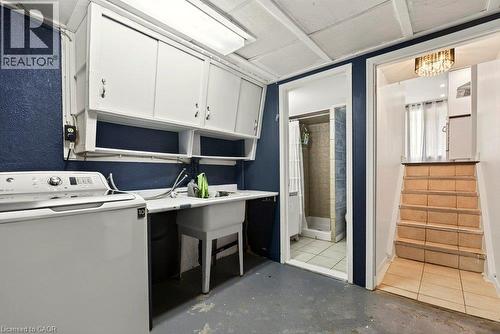 Laundry area with white cabinetry, utility sink, and overhead fluorescent lighting - 27 Gretna Court, Hamilton, ON 