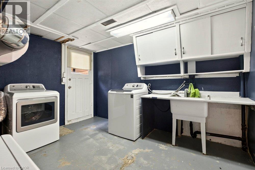 Laundry area featuring a utility sink, integrated countertop, and overhead cabinetry - 27 Gretna Court, Hamilton, ON
