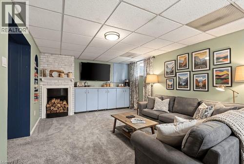Built-in shelving, brick fireplace with mantel, recessed light fixtures, drop ceiling, and light blue base cabinetry - 27 Gretna Court, Hamilton, ON 