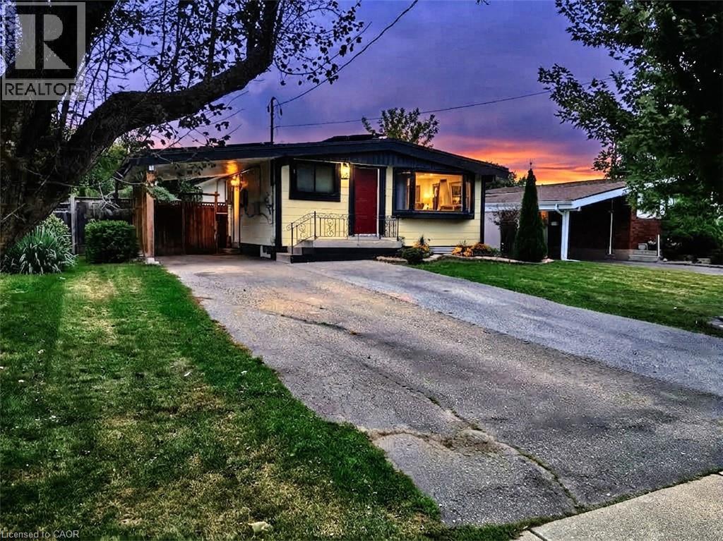 Single-story residence featuring a covered carport, paved driveway, and established landscaping - 134 Deschene Avenue, Hamilton, ON