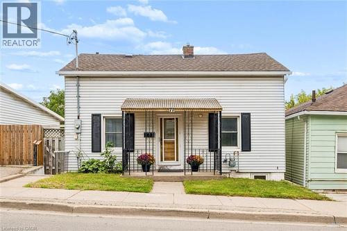 White siding exterior with a covered front porch featuring decorative metal railings - 77 Beverly Street, Cambridge, ON 