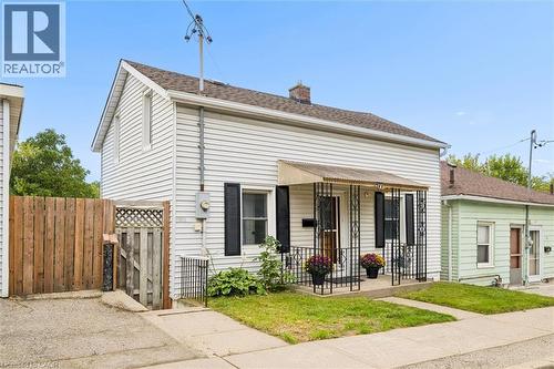 White siding exterior with a pitched roof, front porch with ornate metal railing, and black window shutters - 77 Beverly Street, Cambridge, ON 