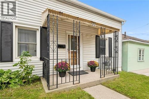 Front porch featuring a decorative awning, wrought iron railings, and a concrete walkway - 77 Beverly Street, Cambridge, ON 